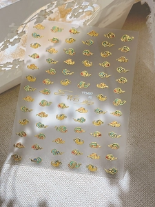 Detailed close-up of golden cloud nail art stickers with intricate metallic borders