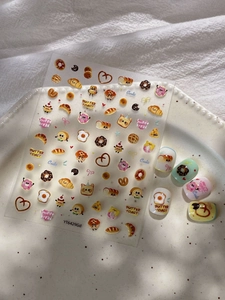 Détails de stickers nail art pain cartoon avec donuts et toasts sur assiette céramique