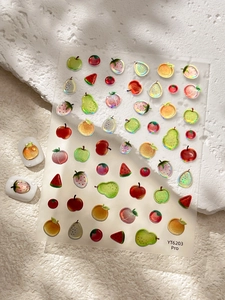 Macro view of 3D fruit nail stickers with iridescent glitter texture and summer motifs
