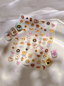 Détail d'autocollants pour ongles avec motifs de pâtisseries, toasts et croissants mignons