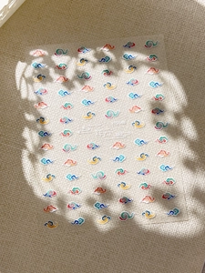 Detailed close-up of colorful traditional Chinese cloud nail art stickers on knit fabric