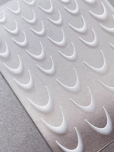 Macro view of white U-shaped French manicure guide stickers on a transparent film