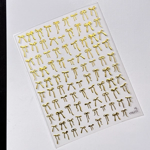 3D golden bow nail art stickers with metallic texture on transparent backing sheet