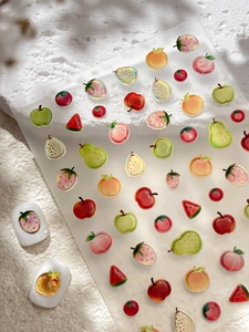 Macro shot of 3D fruit nail art stickers featuring strawberry and apple resin textures