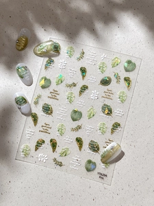 Detail of gold leaf nail stickers with tropical plants and English text decorations
