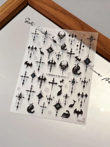 Macro detail of gothic nail art stickers with cross and bat motifs in black and blue