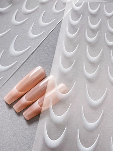 Detail view of French gradient nail stickers and peach-pink manicure tips on gray paper