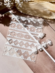 Close-up of white embossed lace nail stickers with floral patterns on fake nails