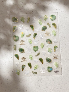 Detail of gold-stamped leaf nail stickers with elegant heart shapes and botanical patterns