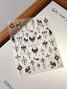 Macro detail of Gothic nail stickers featuring gold foil crosses and star patterns