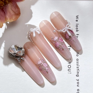 Pink floral press-on nails with 3D bow and pearl accents in long almond shape