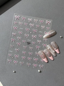 Detail of pink bow nail stickers with crystal rhinestones on a gray background