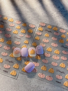 Macro detail of pumpkin nail decals for Halloween featuring relief patterns and orange designs
