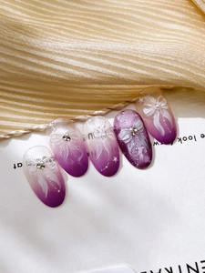 Macro detail of gradient purple press-on nails with 3D bow relief and rhinestone accents