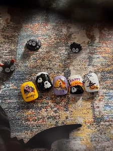Detail of Halloween press-on nails with ghost, witch, and pumpkin embossed designs