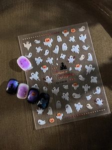 Detail of Halloween nail stickers with ghost and pumpkin patterns on gradient purple nails