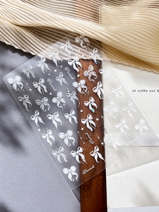 Detailed 5D embossed nail stickers featuring white 3D bows with pearlescent Aurora finish