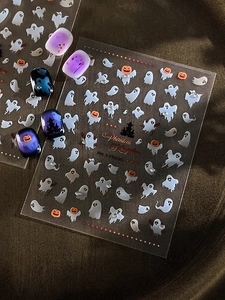 Detail of Halloween nail stickers featuring white ghosts, pumpkins and stars on gradient nails