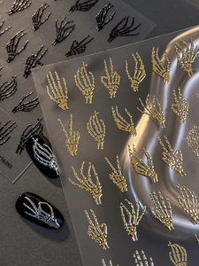 Detail of 3D skeleton hand nail stickers in gold and black for Halloween designs