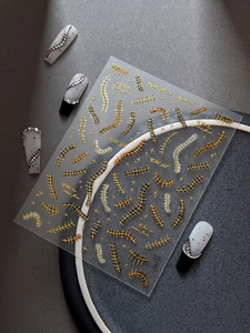 Close-up of 3D gold and silver fishbone relief nail stickers with metallic star details