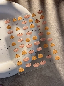 Detail of embossed pumpkin nail stickers with soft pink and orange festive designs