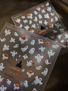 Detail view of Halloween nail art stickers featuring ghosts and pumpkins on dark background