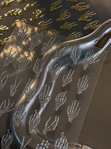 Macro view of gold and silver embossed skeletal hand nail stickers with metallic finish