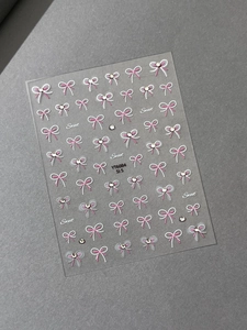 Detailed view of pink and white bow nail stickers with sparkling crystal diamond rhinestones