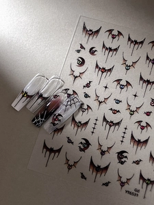 Close-up of Halloween nail stickers with bats and spider webs on a neutral grey background