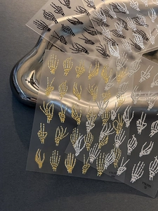 Macro view of 3D embossed skeleton hand nail stickers in gold and silver finish