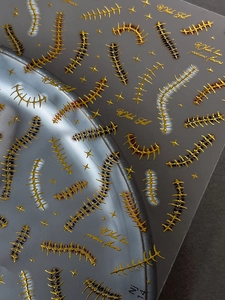 Macro detail of 3D embossed gold and red stitch nail stickers with metallic stars