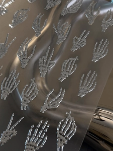 Detailed view of silver chrome skull hand nail stickers with 3D embossed metallic texture