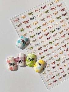 Macro view of 3D bow nail art stickers in various colors on a transparent base