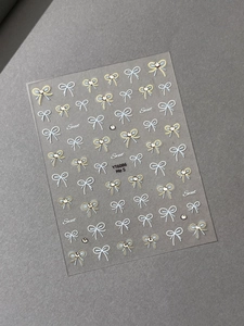 Macro shot of 3D bow nail art stickers with crystal rhinestones in blue and gold