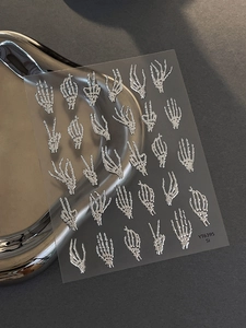 Macro detail of 3D embossed silver bone hand nail stickers for Halloween punk nail art