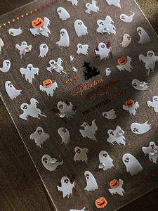 Macro detail of Halloween ghost nail stickers with sparkling rhinestones and pumpkins