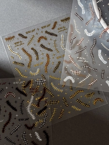 Macro detail of metallic gold spine and chain nail art stickers for gothic manicures