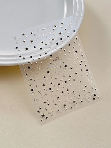 Detail of Starlit Sky nail stickers with black and gold stars on a white plate