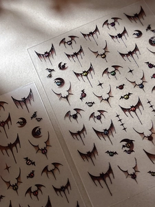 Macro shot of Halloween nail stickers featuring gothic bat wings and colorful eyeballs