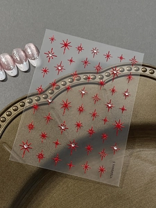 Detailed view of sparkly red star nail stickers with rhinestones on a gold tray