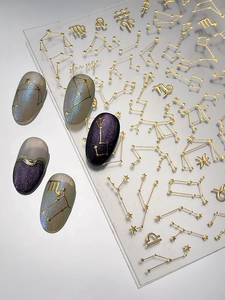 Macro detail of gold constellation nail decals featuring star signs and zodiac patterns