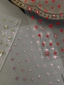Detailed view of shiny gold and red star nail art stickers with small rhinestones