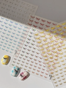 Macro view of 3D embossed bow nail art stickers in gold, silver and laser finishes