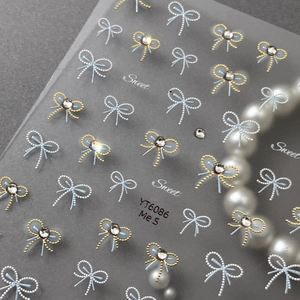 3D bow nail stickers with blue gold patterns and rhinestones on a pearly background