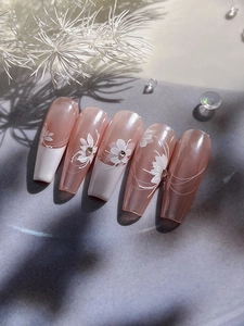 Macro detail of long coffin nails with pearl pink base and white floral rhinestone art