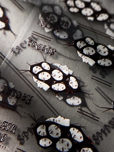 Detail shot of Halloween nail stickers featuring dark spider and female face art designs