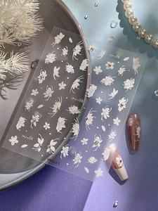 Detail showing 3D embossed white flower and butterfly nail art stickers with small rhinestones