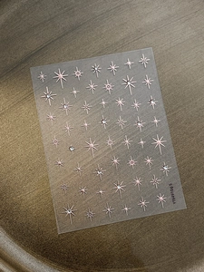 Detail of rose gold hexagram nail stickers with sparkling crystals on bronze tray