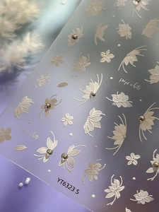 Macro detail of 5D embossed white flower and butterfly nail stickers with silver rhinestones