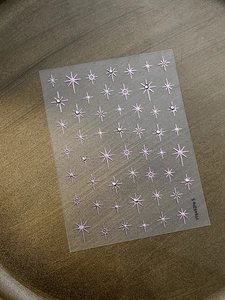 Detail of pink starburst nail stickers with 3D crystal rhinestones on dark metal